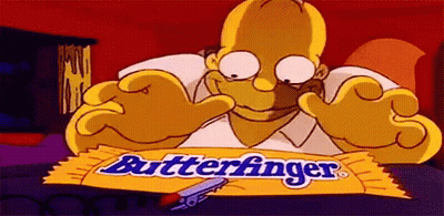 Homer Simpson Is Sitting At A Table With A Wrapper Of Butterfinger Chocolate Bar . GIF