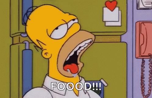 Homer Simpson Is Sitting In Front Of A Refrigerator With His Mouth Open And His Tongue Out . GIF