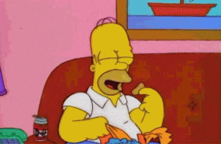 Homer Simpson Is Sitting On A Red Couch Eating Chips GIF