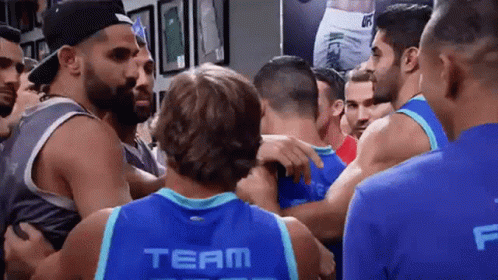 Huddled Men, One In Blue Team Jersey GIF