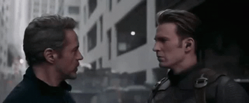 Iron Man And Captain America Are Standing Next To Each Other And Looking At Each Other In Front Of A Building . GIF
