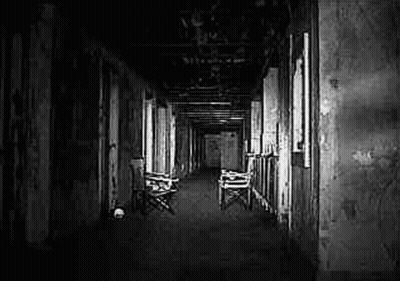 It Is A Black And White Photo Of A Long Hallway With Chairs . GIF