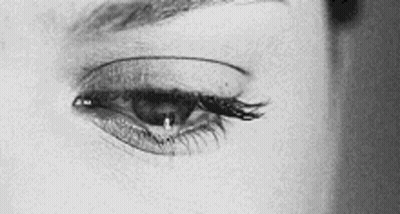 It Is A Black And White Photo Of A Woman 'S Eye With A Tear Coming Out Of It . GIF