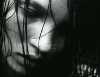 It Is A Black And White Photo Of A Woman 'S Face With Long Hair . GIF