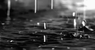 It Is A Black And White Photo Of Rain Falling On A Puddle Of Water . GIF