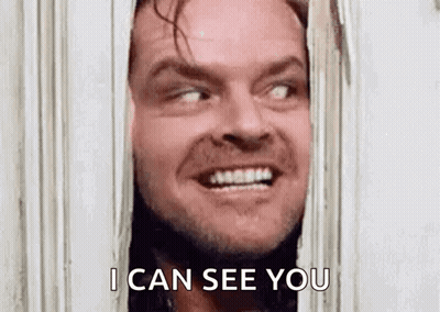 Jack Nicholson From The Shining Is Smiling While Looking Through A Door . GIF