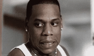 Jay Z Is Wearing A White Tank Top And A Necklace And Looking At The Camera . GIF