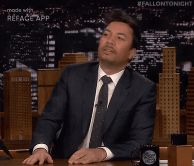 Jimmy Fallon Is Sitting At A Table With A Fallon Tonight Mug GIF