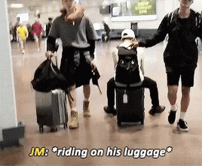 JM Riding on Luggage While Man Sits on Suitcase