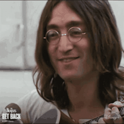 John Lennon Is Wearing Glasses And Holding A Guitar . GIF