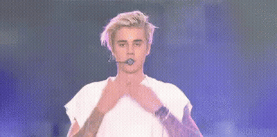 Justin Bieber Is Holding A Microphone In His Mouth And Says `` Love All My Beliebers '' . GIF
