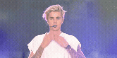 Justin Bieber Is Kissing Someone On The Cheek On Stage While Holding A Microphone . GIF