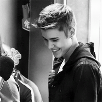 Justin Bieber Is Smiling In A Black And White Photo While Standing In Front Of A Microphone . GIF
