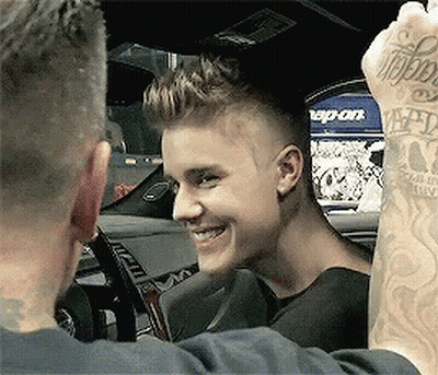 Justin Bieber Is Smiling While Sitting In A Car With A Snap-On Sign In The Background GIF