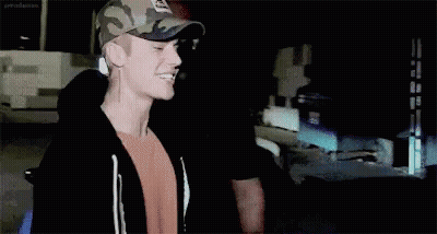 Justin Bieber Is Wearing A Camouflage Hat And Smiling . GIF