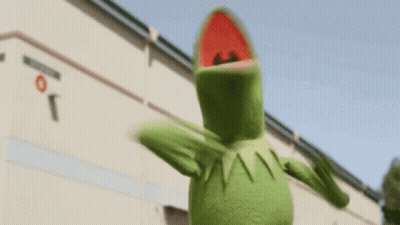 Kermit The Frog Is Standing In Front Of A Building . GIF