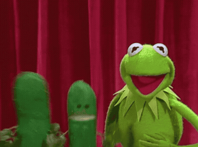 Kermit The Frog Is Standing Next To A Pickle On A Stage GIF