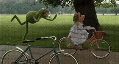 Kermit The Frog Is Standing On Top Of A Bicycle Next To A Muppet Riding A Bicycle . GIF