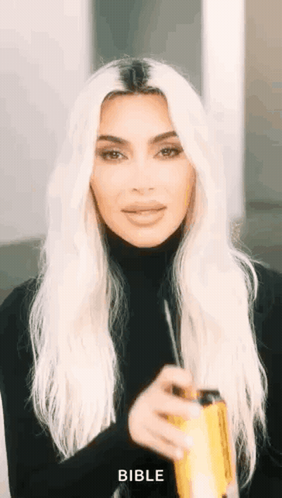Kim Kardashian Is Wearing A Black Turtleneck And Holding A Can Of Soda In Her Hand . GIF