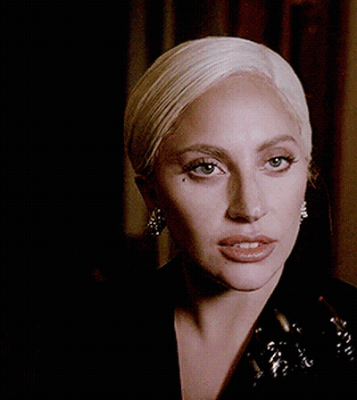 Lady Gaga In Black Jacket Holding Trophy In Mouth GIF