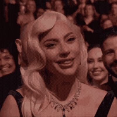Lady Gaga Is Smiling While Sitting In A Crowd Of People . GIF