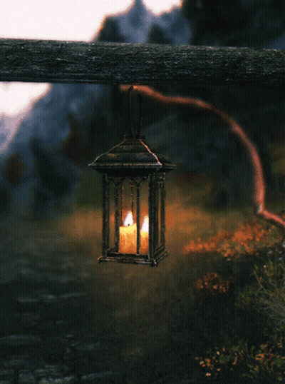 Lantern With Lit Candle Hanging From Wooden Post GIF
