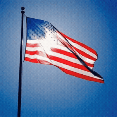 Large American Flag Flying In Wind Blue Sky GIF