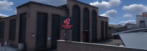 Large Brick Building With Flywheels Garage Sign GIF