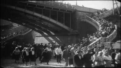 Large Crowd Walking Under Bridge GIF