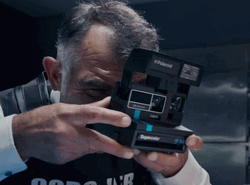 Le Coroner Using Polaroid Camera