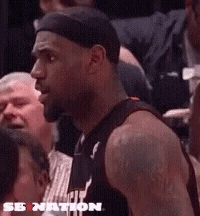 Lebron James Is Sitting In The Stands Watching A Basketball Game And Talking To A Referee . GIF
