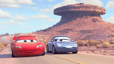 Lightning Mcqueen And Sally Are Driving Down A Desert Road GIF