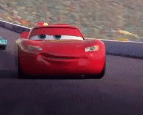 Lightning Mcqueen From Cars Is Driving Down A Race Track GIF