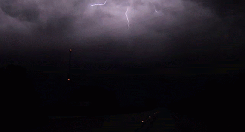 Lightning Strikes Over A Dark Road With A Street Light In The Foreground GIF