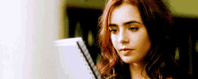 Lily Collins Looking Up From A Book GIF