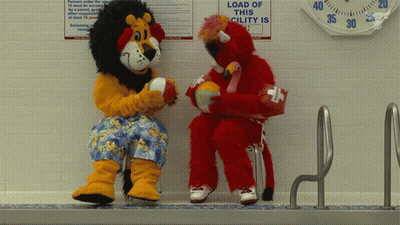 Lion And Flamingo Mascot Sitting Near Load Of This Cility Sign GIF