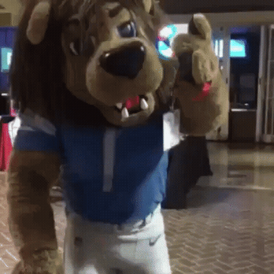 Lion Mascot In Blue Shirt And White Shorts GIF