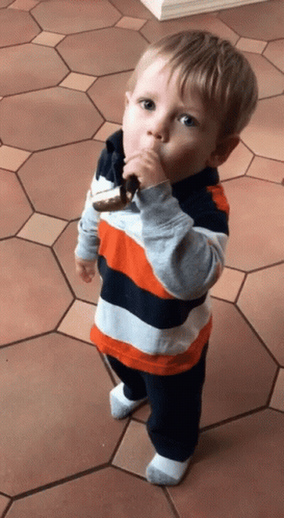 Little Boy Eating Cookie On Tiled Floor GIF