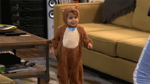 Little Boy In Bear Costume Standing In Front Of Couch GIF