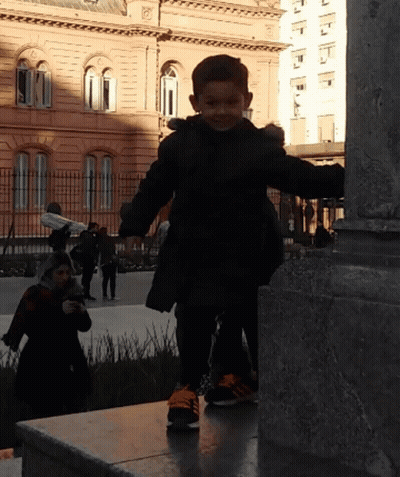 Little Boy In Black Jacket And Orange Shoes On Ledge GIF