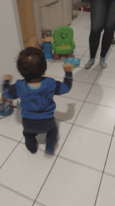 Little Boy In Blue Shark Shirt Walking To Green Toy Chair GIF