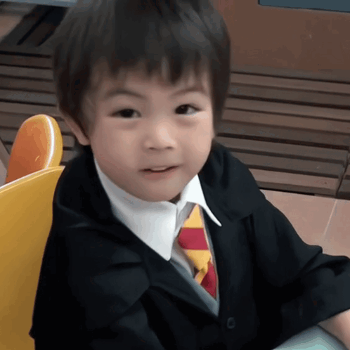 Little Boy In Suit And Tie Sitting In Yellow Chair GIF