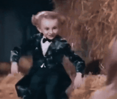 Little Boy In Tuxedo And Bow Tie Dancing In Dark Room GIF