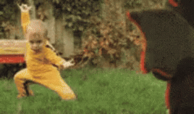 Little Boy In Yellow Practicing Martial Arts With Black Bear GIF