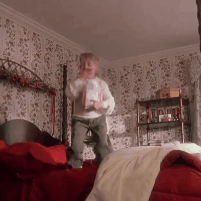 Little Boy Jumping On Bed Holding Book GIF