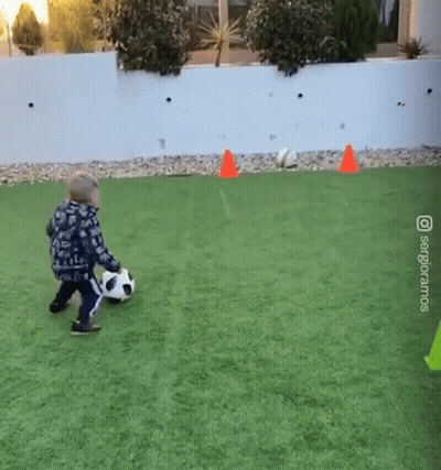 Little Boy Kicking Soccer Ball On Green Field GIF
