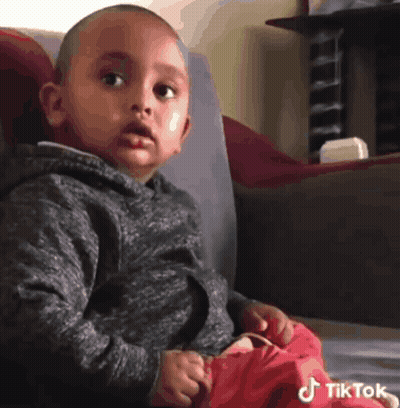 Little Boy On Couch Looking At Camera With TikTok Logo GIF