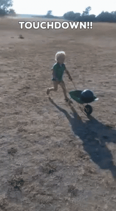 Little Boy Pushing Wheelbarrow On Beach Saying Touchdown GIF