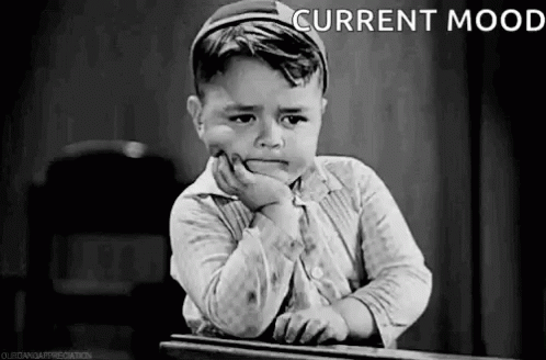 Little Boy Sitting At Desk With Hand On Chin And Sad Face GIF