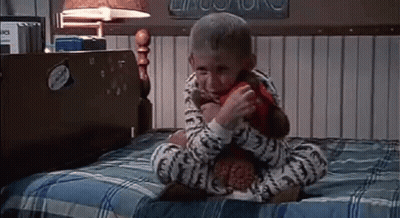 Little Boy Sitting On Bed With Stuffed Animal GIF